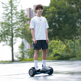Person riding a hoverboard on a path with trees and buildings in the background